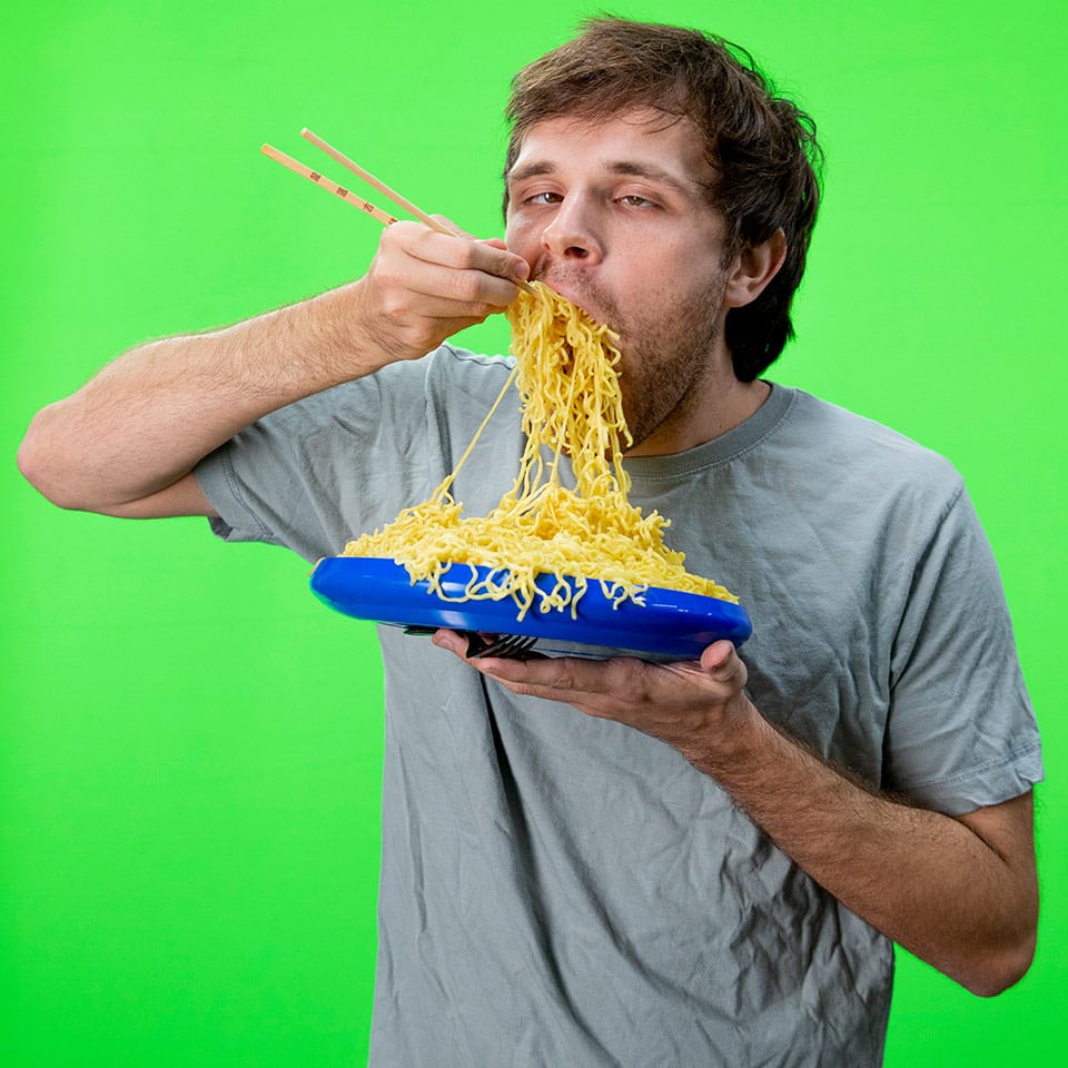 A green screen shot of an actor eating ramen noodles