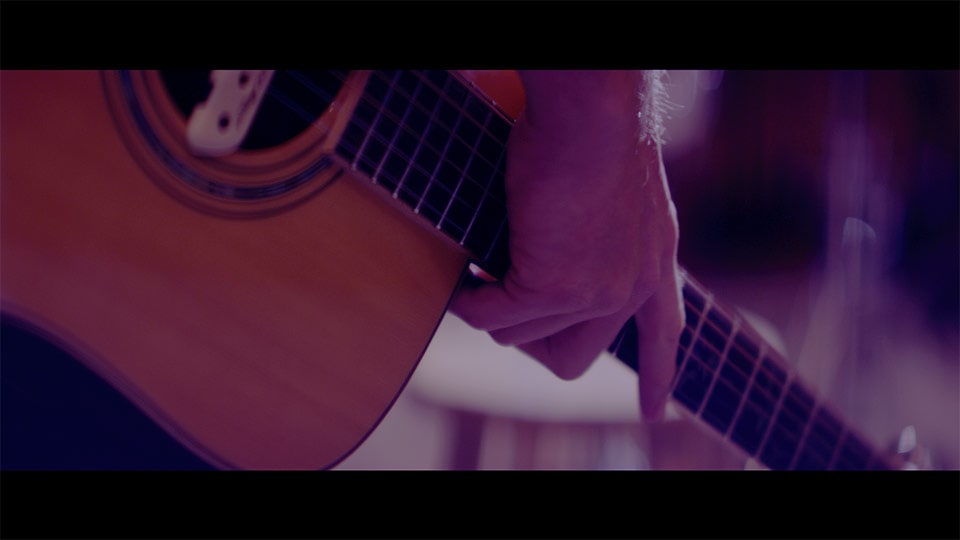 A closeup of a guitar in a branded documentary video